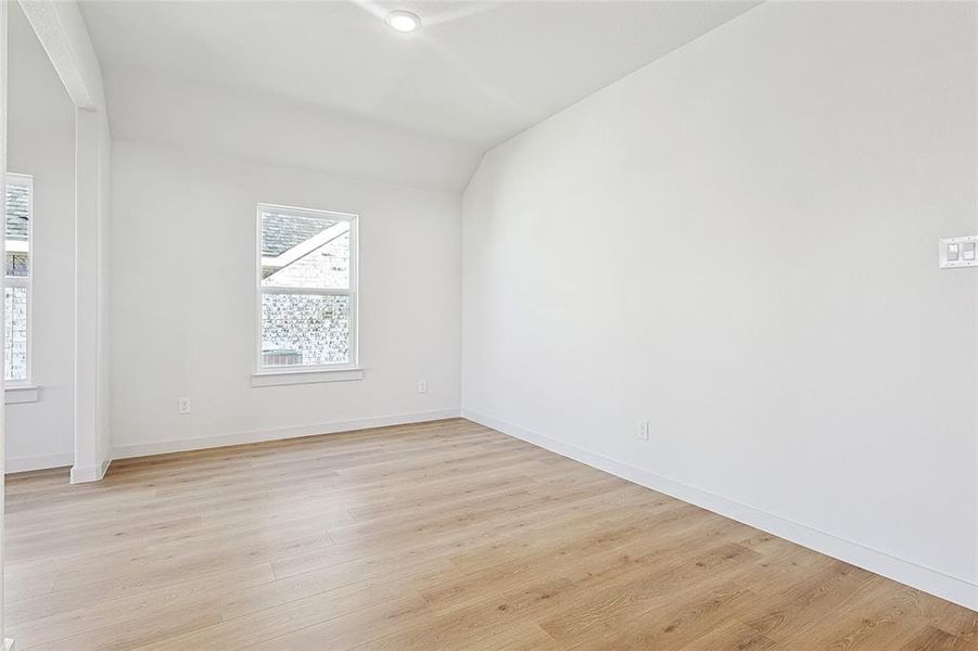 Empty room with light hardwood / wood-style floors and lofted ceiling