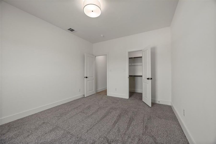 Unfurnished bedroom with dark colored carpet and a closet