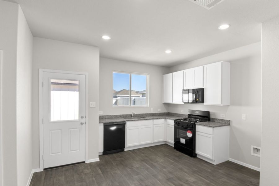 Image of a kitchen with white cabinets, granite countertops, black appliances and a white back door