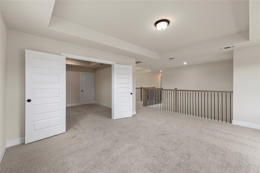 Spare room featuring a raised ceiling, light colored carpet, and recessed lighting