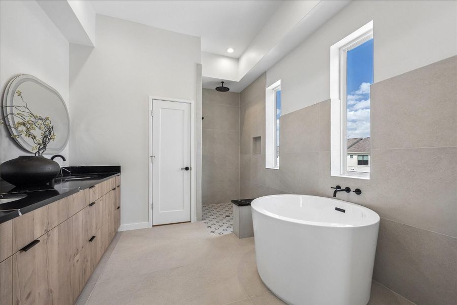 Spa inspired primary bathroom featuring a freestanding soaking tub, oversized walk-in shower, dual vanity, and abundant natural light. Spa inspired primary bathroom featuring a freestanding soaking tub, oversized walk-in shower, dual vanity, and abundant natural light.