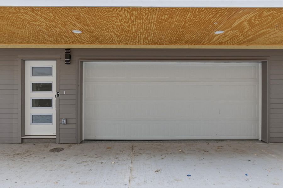 White garage door with an adjacent entry door featuring four horizontal window panes