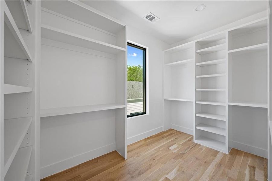 Primary walk in closet with light wood-type flooring. Primary walk in closet with light wood-type flooring.