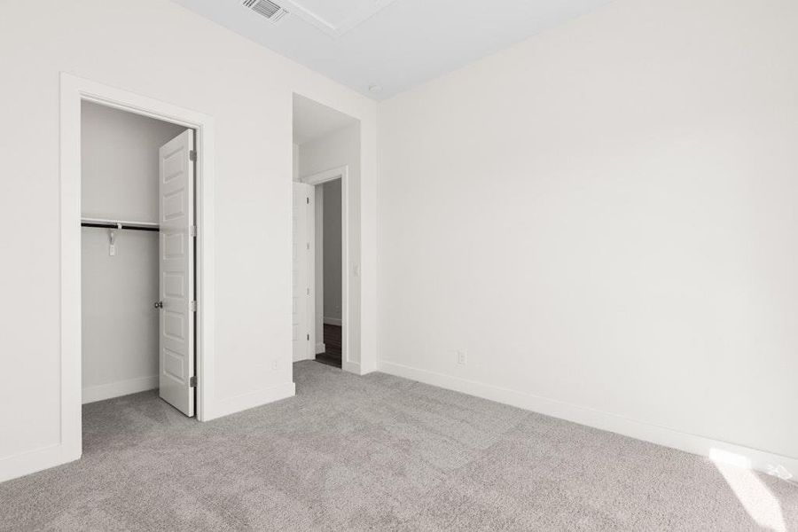 Unfurnished bedroom featuring a walk in closet and light carpet Unfurnished bedroom featuring a walk in closet and light carpet