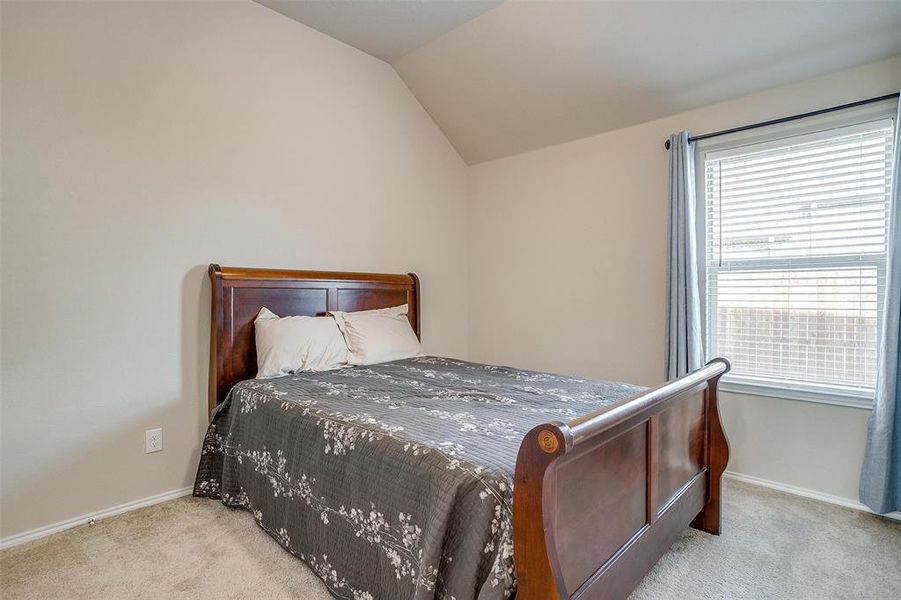 Carpeted bedroom featuring vaulted ceiling