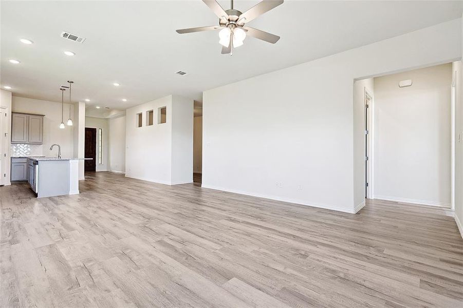 Unfurnished living room with light hardwood / wood-style floors, ceiling fan, and sink