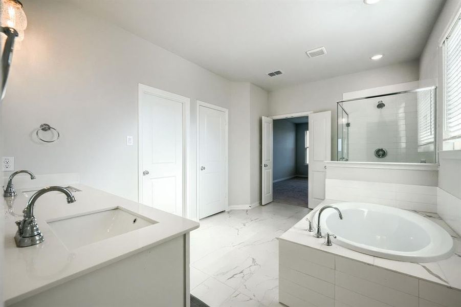 Bathroom with double vanity, a garden tub, a shower stall, light marble finish floors, and recessed lighting Bathroom with double vanity, a garden tub, a shower stall, light marble finish floors, and recessed lighting