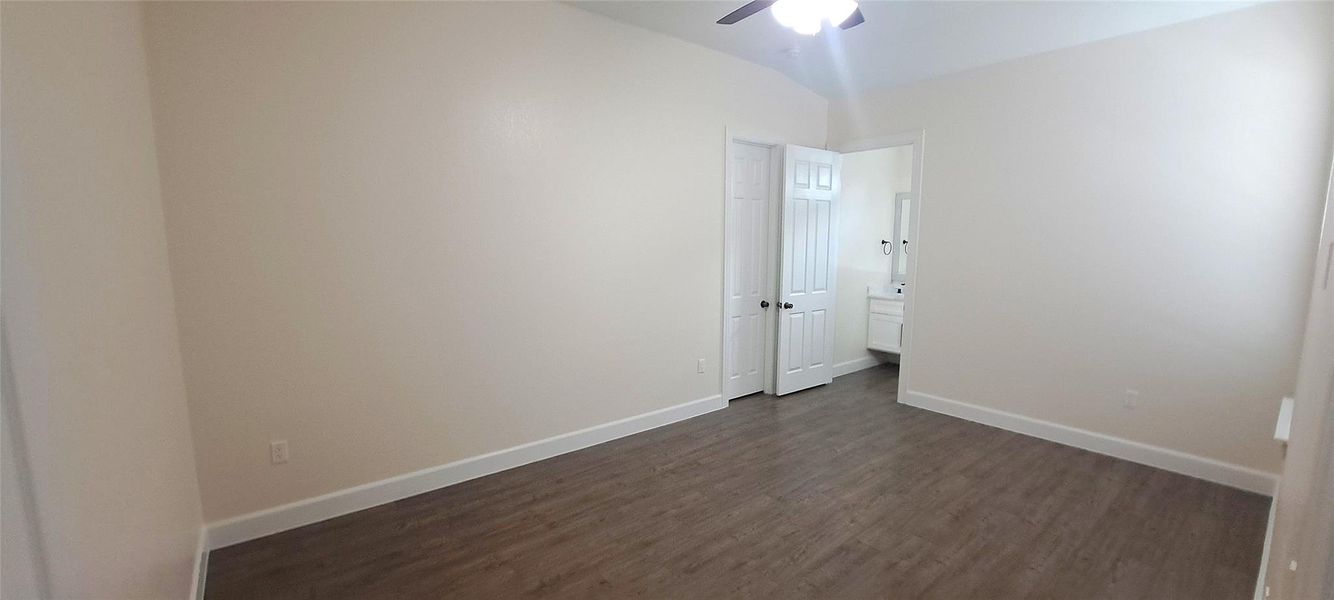 Empty room with dark wood-style flooring and a ceiling fan