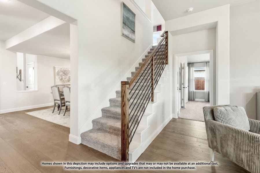 Carpeted staircase with wood and metal railing in open entryway with hardwood floors and white walls Carpeted staircase with wood and metal railing in open entryway with hardwood floors and white walls