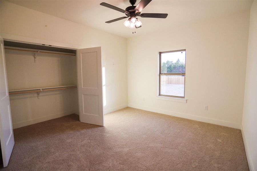 Unfurnished bedroom featuring light carpet, a closet, and a ceiling fan