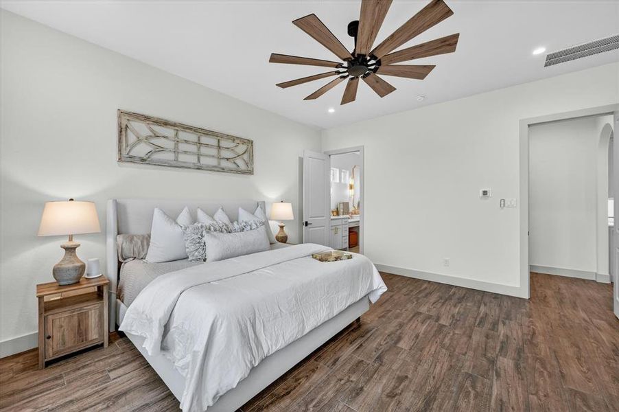 Spacious interior room featuring wood-finish flooring, a contemporary ceiling fan with wooden blades, recessed lighting, and a neutral color palette