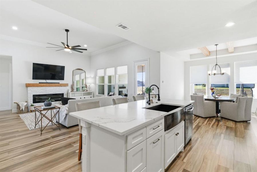 Kitchen with open floor plan, a fireplace, recessed lighting, white cabinetry, and light stone countertops