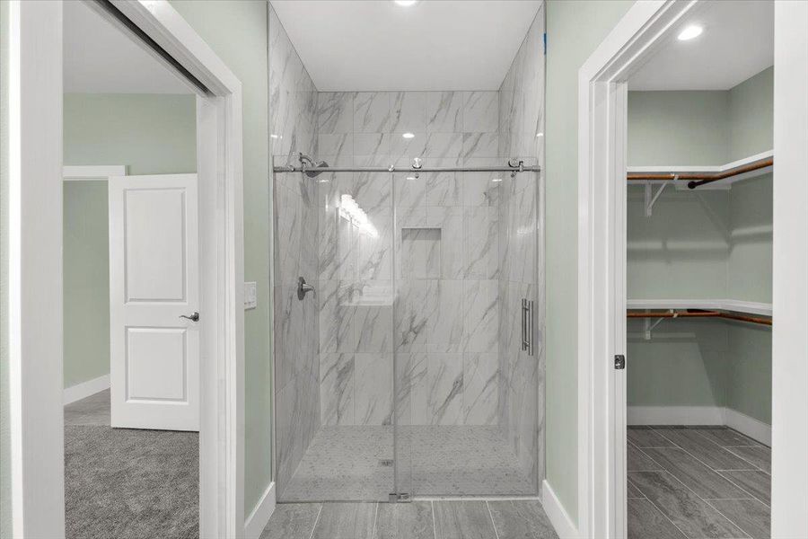 Primary Full bath with a marble finish shower and a walk in closet