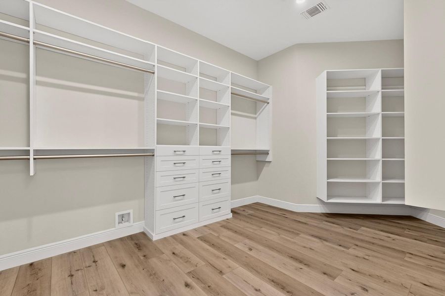Custom built-in shelving and smooth wood-texture floors define this organized wardrobe space.