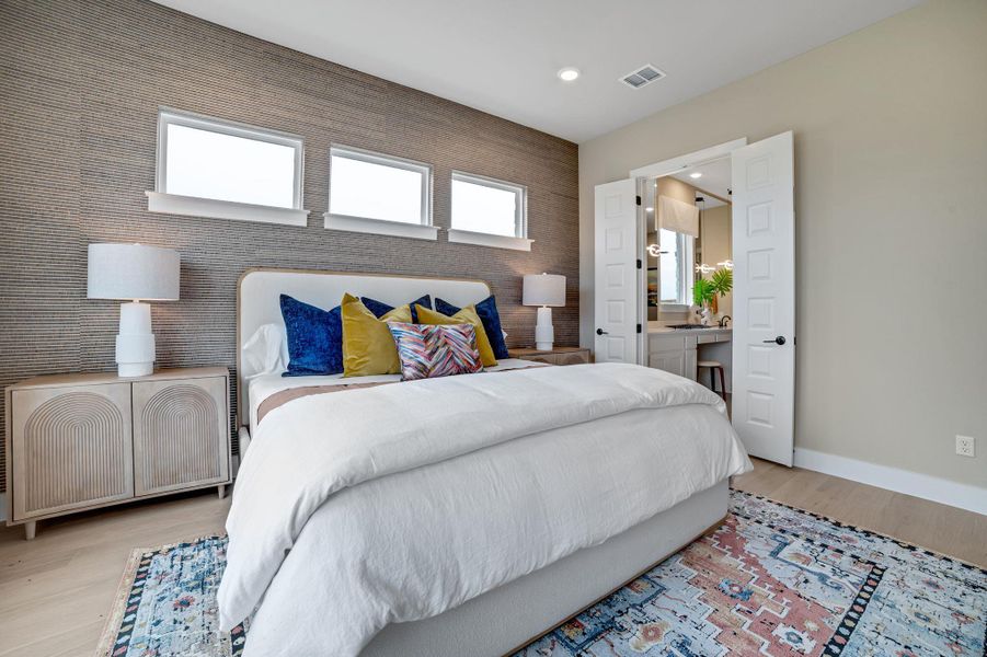 Bedroom with an accent wall, light wood-style floors, connected bathroom, and recessed lighting
