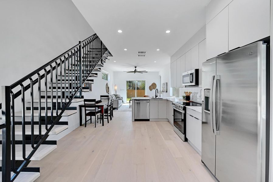 Kitchen featuring a sink, stainless steel appliances, modern cabinets, and a ceiling fan