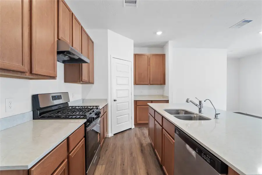 A true chef’s dream, this expansive kitchen boasts high ceilings, rich stained wood cabinets, Silestone countertops in Lusso, stainless steel appliances, recessed lighting, extended counter space, an island with added breakfast bar, and a walk-in pantry—all with a clear view of the spacious family room.