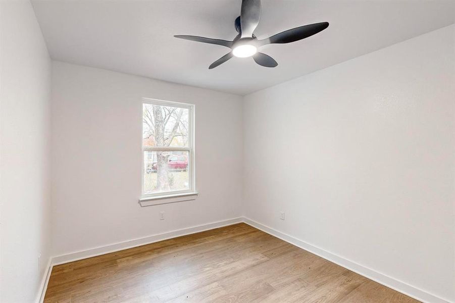 Empty room with ceiling fan and light hardwood / wood-style floors