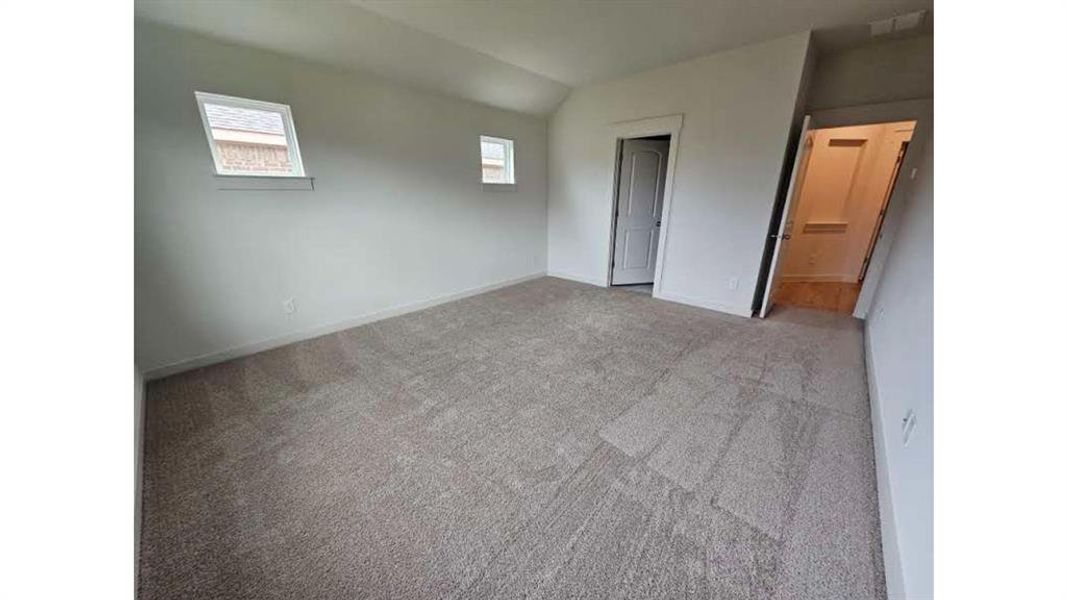 Spacious room featuring neutral carpeting, white walls, and two windows
