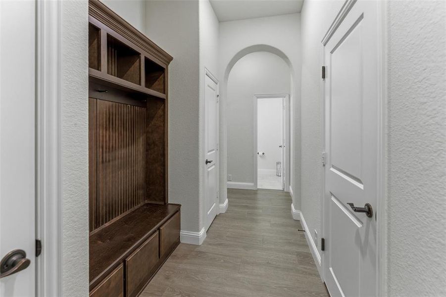 Mudroom with arched walkways and light wood-style flooring
