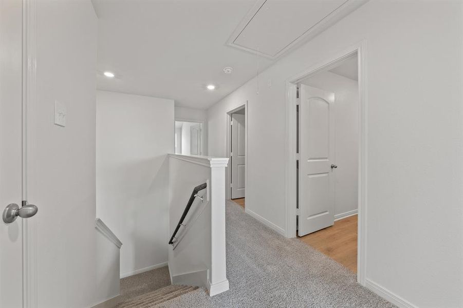 Hall with an upstairs landing, light colored carpet, attic access, and recessed lighting Hall with an upstairs landing, light colored carpet, attic access, and recessed lighting