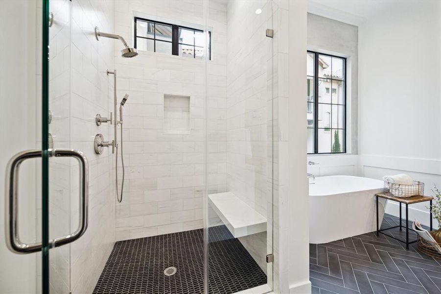 The bathroom has a walk-in shower with tile walls, frameless glass door, built-in shower niche, and stone bench seating, alongside herringbone ceramic tile flooring. An aluminum window offers northern exposure.