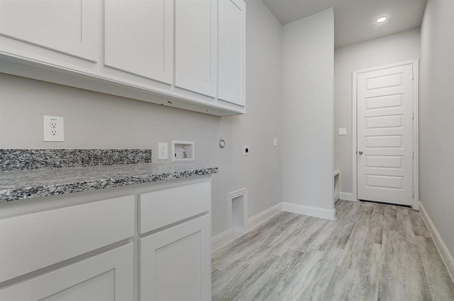 Clothes washing area featuring cabinets, washer hookup, light hardwood / wood-style flooring, and electric dryer hookup