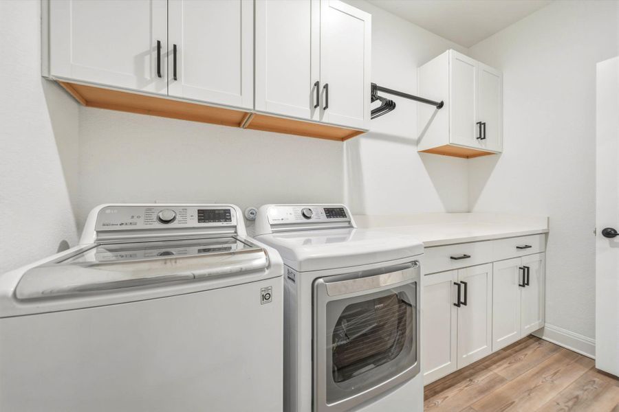 Laundry room featuring white cabinetry, a built-in hanging rod, and quartz countertops