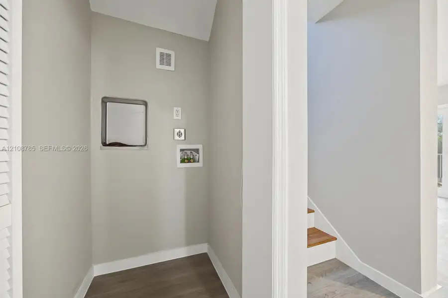 Neutral interior alcove featuring wood-finish flooring and integrated wall-mounted utility access panels Neutral interior alcove featuring wood-finish flooring and integrated wall-mounted utility access panels