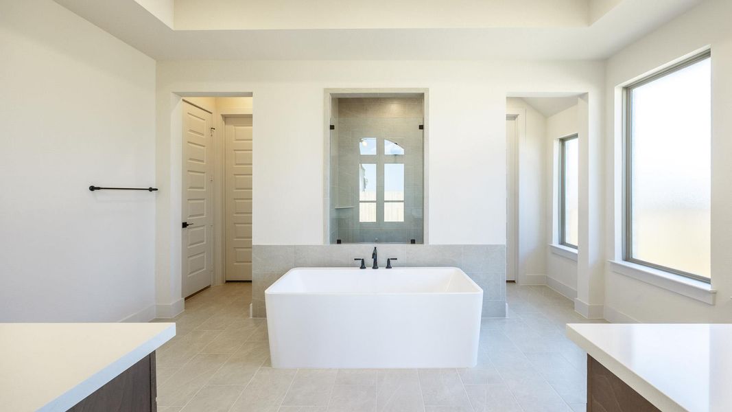 Full bath featuring healthy amount of natural light, a soaking tub, and light tile patterned floors