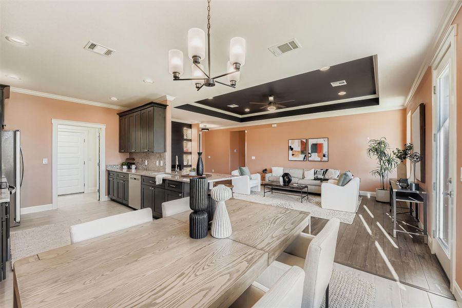 Dining room with a chandelier, ornamental molding, ceiling fan, recessed lighting, and a raised ceiling
