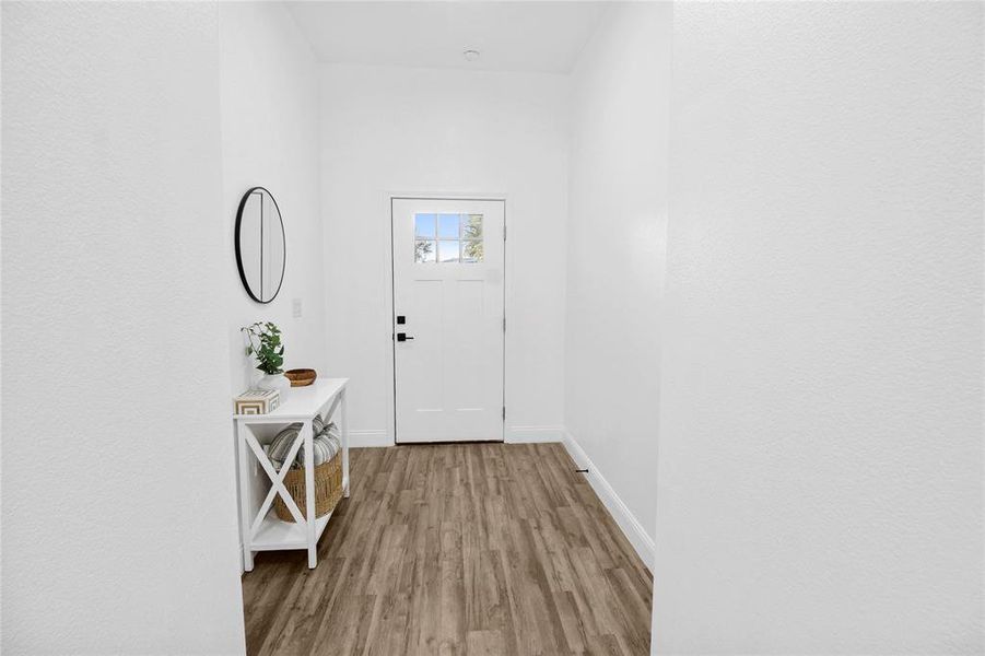 Doorway to outside featuring wood finished floors and baseboards Doorway to outside featuring wood finished floors and baseboards