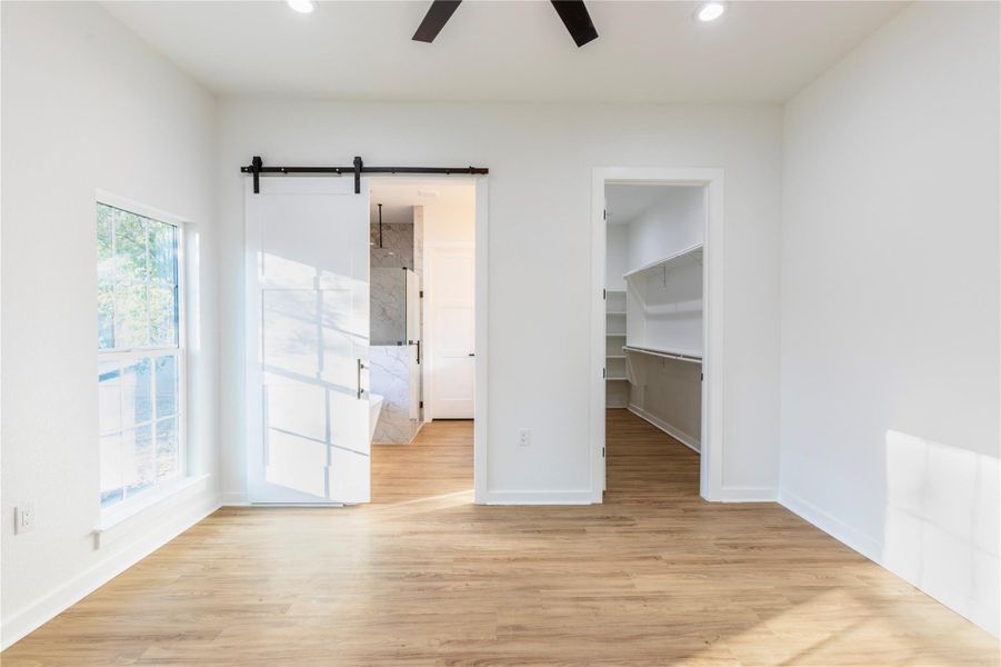 Barn doors opening to reveal the primary bathroom.