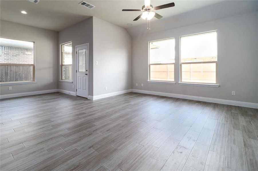 Empty room with ceiling fan, a wealth of natural light, and light hardwood / wood-style floors