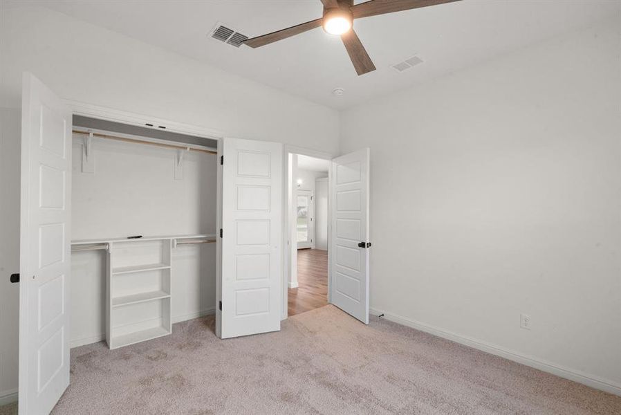 Unfurnished bedroom featuring ceiling fan, a closet, and light carpet Unfurnished bedroom featuring ceiling fan, a closet, and light carpet
