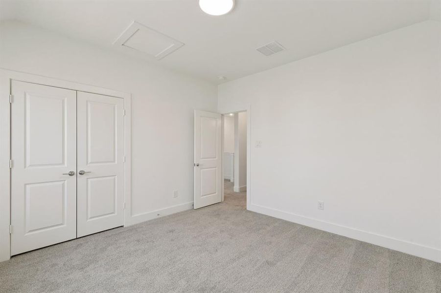 Unfurnished bedroom with carpet floors, attic access, and a closet Unfurnished bedroom with carpet floors, attic access, and a closet