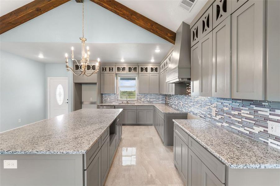 Kitchen featuring backsplash, vaulted ceiling with beams, a kitchen island, and wall chimney range hood