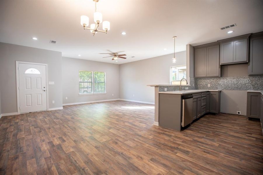 Kitchen with tasteful backsplash, dark wood-type flooring, ceiling fan with notable chandelier, gray cabinets, and decorative light fixtures