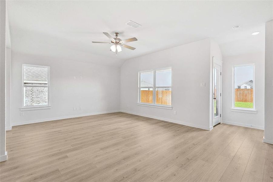 Unfurnished room with ceiling fan, light wood-type flooring, and lofted ceiling