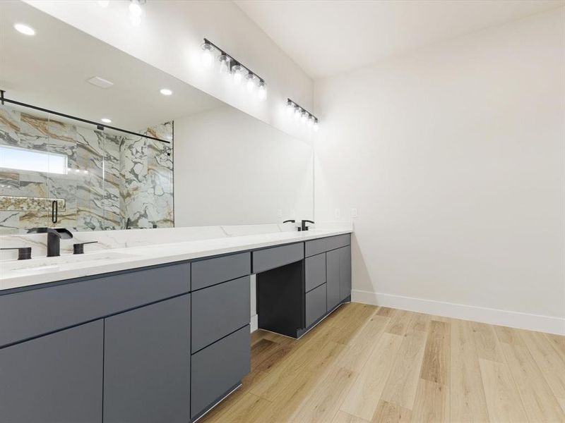 Bathroom with a marble finish shower, double vanity, light wood-type flooring, and recessed lighting