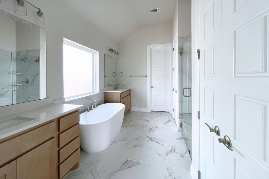 Indulge in a tranquil bathing experience in this well-appointed bath with a freestanding tub and double vanities.