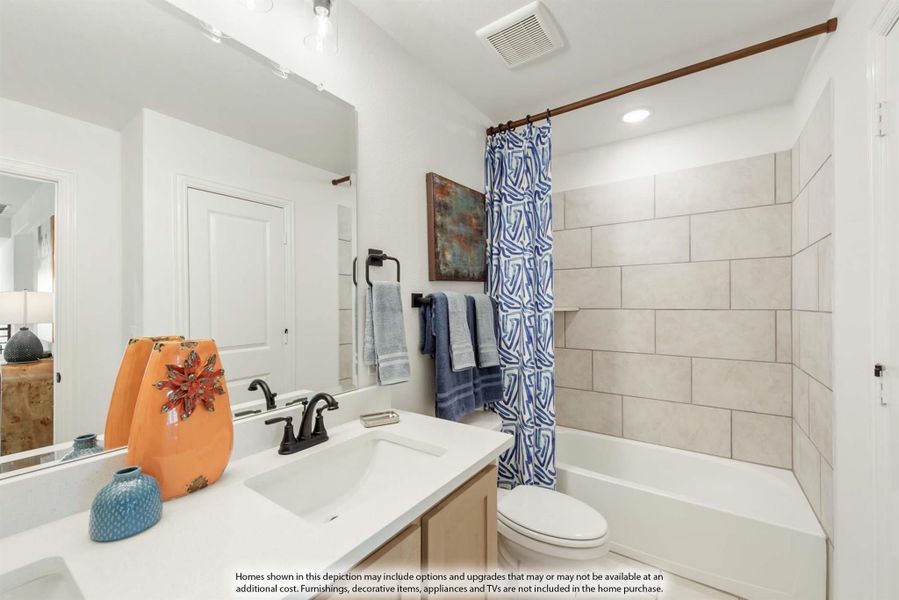 Bathroom with single vanity, toilet, and tiled bathtub with blue shower curtain