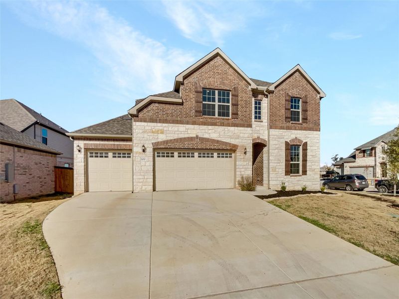 View of front facade with concrete driveway, an attached garage, brick siding, and a shingled roof