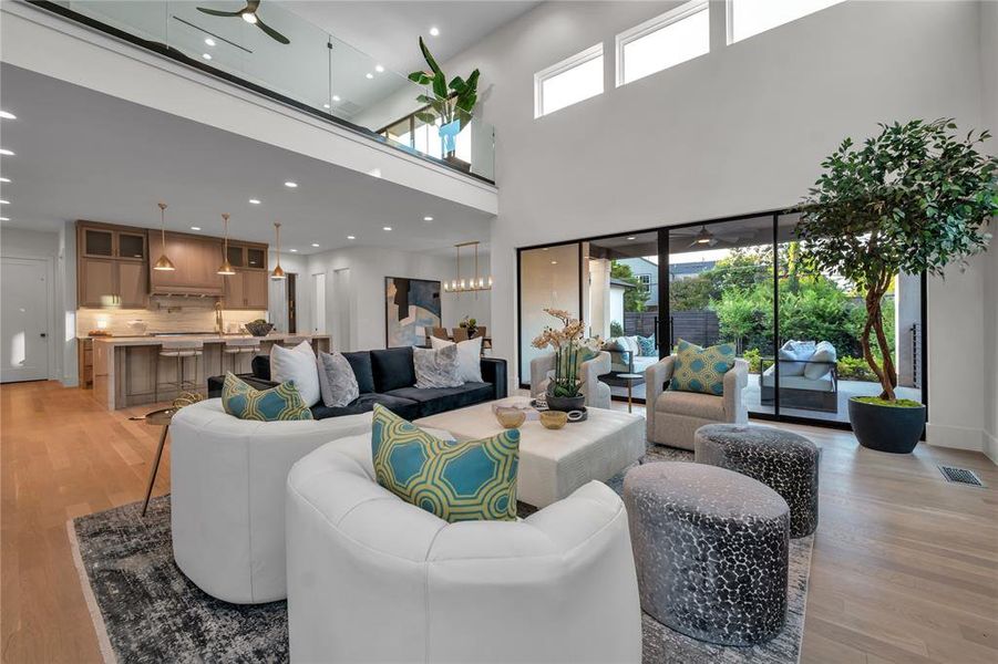 Living room with ceiling fan, light wood-style floors, recessed lighting, and a towering ceiling Living room with ceiling fan, light wood-style floors, recessed lighting, and a towering ceiling