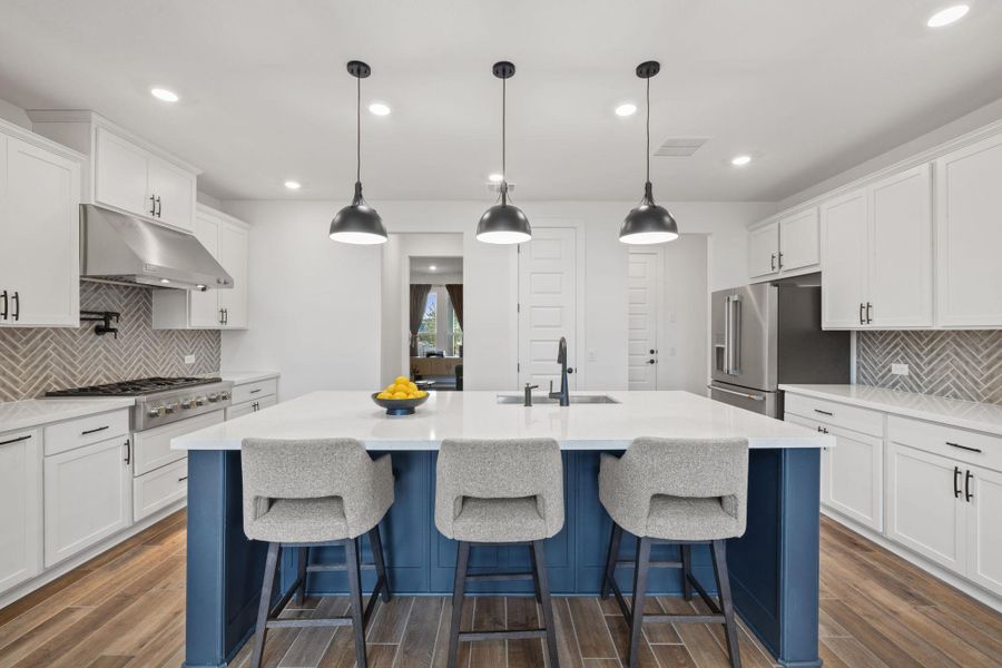 Kitchen island, white cabinets, blue & white island, stainless steel appliances, and recessed lighting