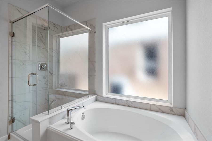 This master bathroom is definitely move-in ready! Featuring a framed walk-in shower with tile surround, separate garden tub for soaking after a long day!