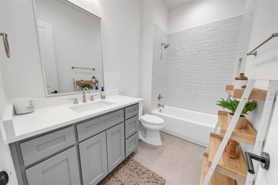 Full guest bathroom featuring vanity, toilet, tiled shower / bath, and tile patterned flooring