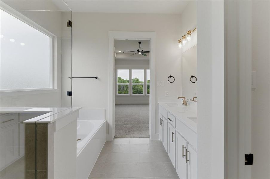 Contemporary bathroom featuring dual vanities with white cabinetry and light-toned countertops, a built-in tub, and a separate shower with a clear glass enclosure
