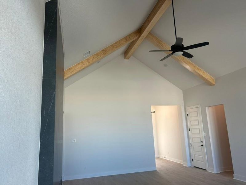 Empty room featuring beam ceiling, high vaulted ceiling, ceiling fan, and wood finished floors Empty room featuring beam ceiling, high vaulted ceiling, ceiling fan, and wood finished floors