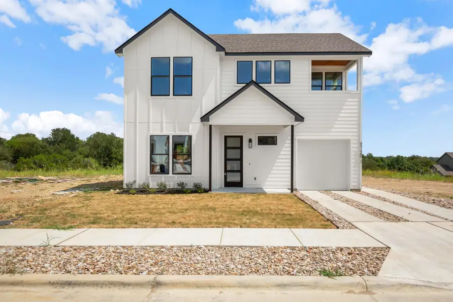 Modern farmhouse style home featuring driveway, board and batten siding, an attached garage, roof with shingles, and a front yard